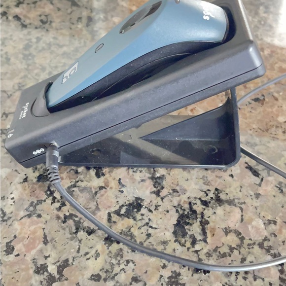 This is a blue Socket Mobile barcode scanner with a charging stand and cord. - Picture 3 of 3